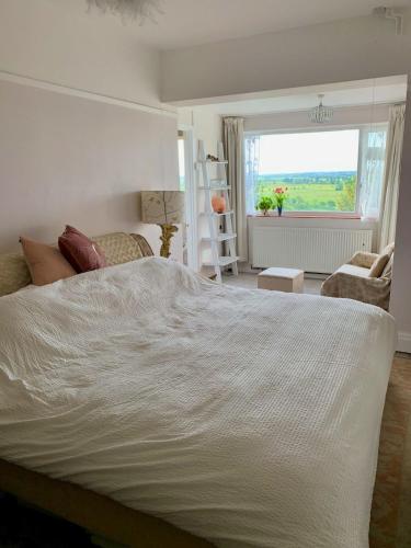 a bedroom with a large white bed and a window at Magic of Avalon in Glastonbury