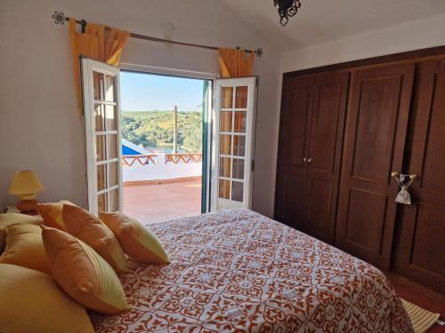 a bedroom with a bed and a door to a balcony at Casa dos Alpendres in Avis