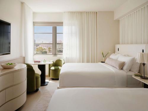 a white hotel room with two beds and a table at Delano Miami Beach in Miami Beach