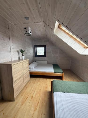 a attic bedroom with a bed and a window at Domki Malibu in Tupadła