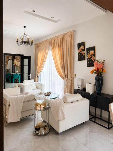 a living room with white furniture and a large window at Le Refuge du Lac Rose in Ouayembame