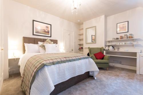 a bedroom with a bed and a green chair at April House Weybridge - Boutique Guesthouse in Weybridge