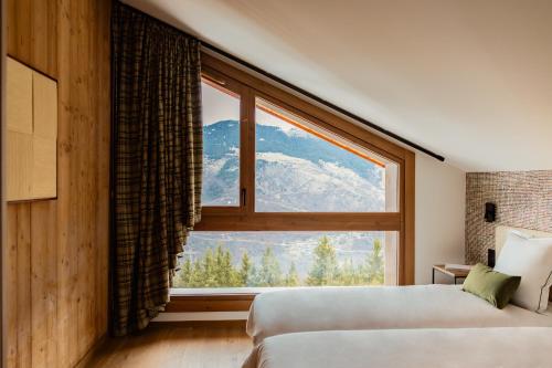 a bedroom with a large window with a mountain view at Barma Résidence & Appartements in Courchevel