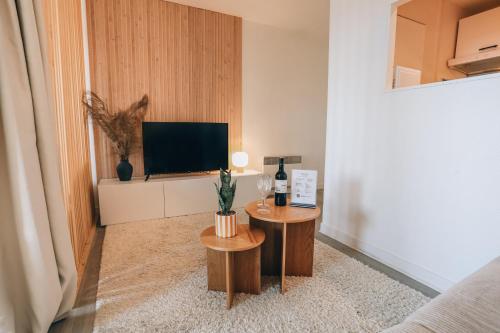 a living room with two tables and a flat screen tv at Vue mer, sur le port, près des tours in La Rochelle