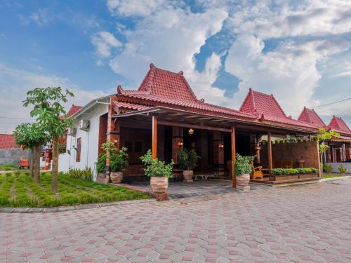 a house with a red roof on a brick street at Griya Mandara Homestay Prambanan in Bugisan