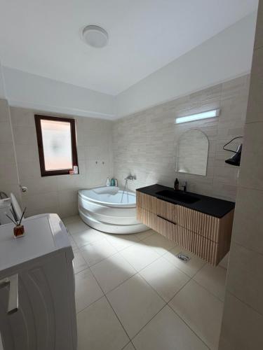 a white bathroom with a tub and a sink at Apartament Valcea in Râmnicu Vâlcea