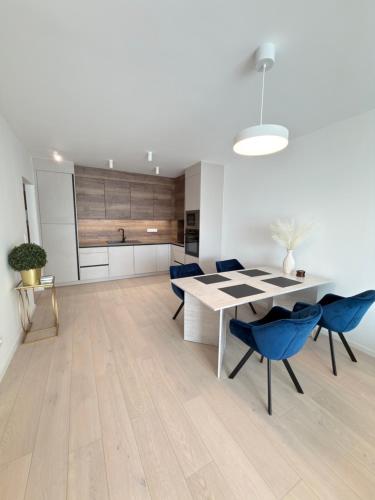 a kitchen and dining room with a table and blue chairs at Anna Lakeside Apartman in Gárdony