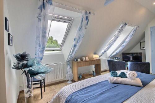 a bedroom with a blue bed and a window at Les Gîtes Shu-no in Pléhédel