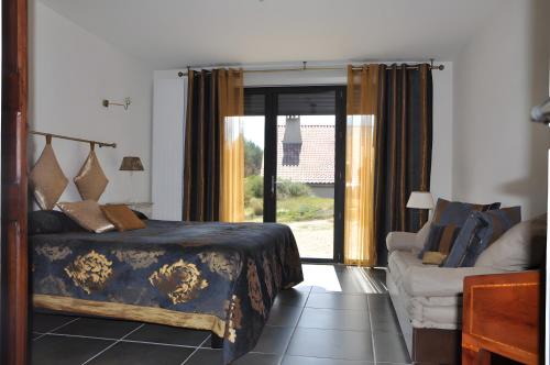 a bedroom with a bed and a couch and a window at Domaine De Jassenove in Millau