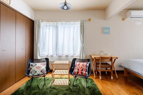 a bedroom with two chairs and a table and a bed at つぐ屋札幌 in Sapporo