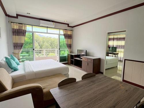 a bedroom with a bed and a table and a window at Breezehill Khao Kho Hotel in Khao Kho