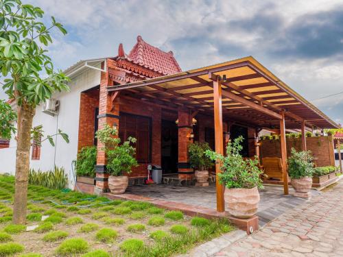 a house with a wooden pergola with potted plants at Griya Mandara Homestay Prambanan in Bugisan