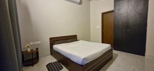 a small bedroom with a bed and a wooden cabinet at Villa Riviera in Covelong