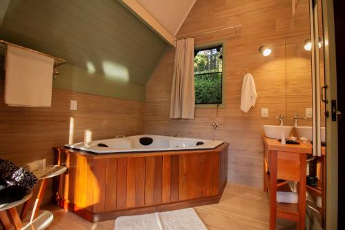 a large bathroom with a tub and a sink at Pousada & Spa Cantos e Contos in Monte Verde