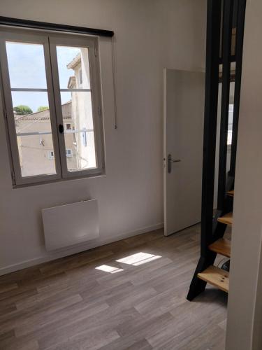 an empty room with a window and a staircase at Studio le 174 in Mazan