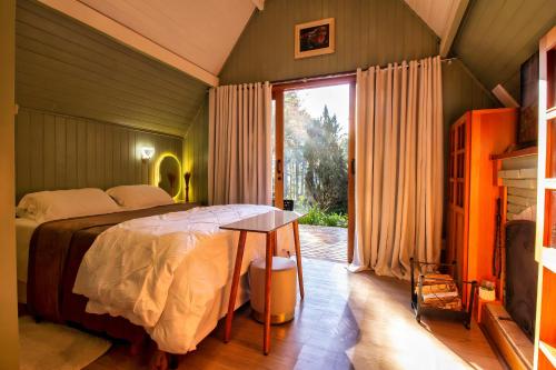 a bedroom with a bed and a table and a window at Pousada & Spa Cantos e Contos in Monte Verde