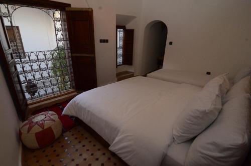 a bedroom with a white bed and a window at Le Cèdre D'argent in Fès