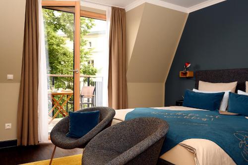 a bedroom with a bed and two chairs and a window at THE GREEN Rostock Apartment Hotel in Rostock