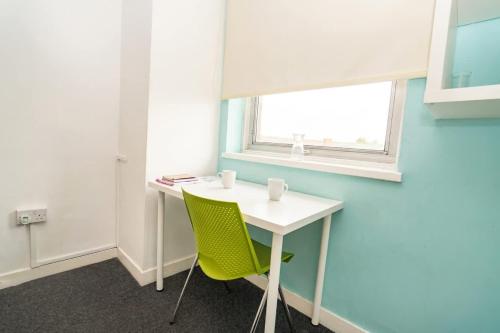 a desk with a green chair in a room with a window at Budget En-suite Room in Coventry City Centre in Coventry