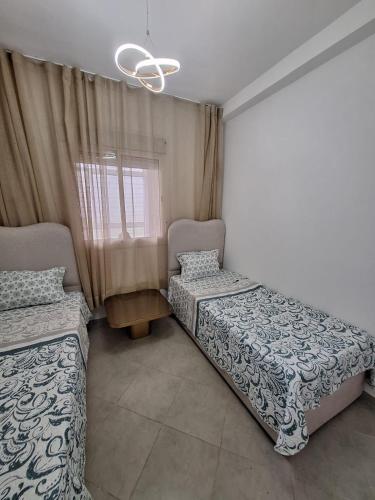 a bedroom with two beds and a chandelier at Super Appartement Sidi Rhal in Dar Hamida