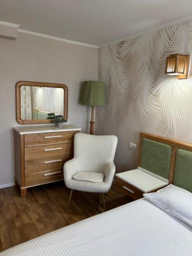 a bedroom with a bed and a chair and a mirror at Простора та стильна 2 кімнатна в центрі Черкас на бульварі Шевченко з панорамним видом та СмартТВ! Дві окремі охайні спальні з кондиціонерами,поруч парковка з охороною in Cherkasy