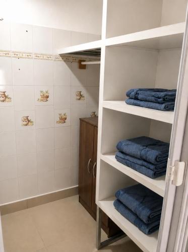 a bathroom with white shelves with blue towels at Casa Solymar completa 3 dormitorios 5 camas Hasta 6 personas RESERVAS SOLO CON SEÑA in Ciudad de la Costa