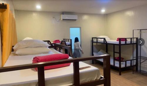 a woman walking through a room with bunk beds at Janisah Pension House in Narra