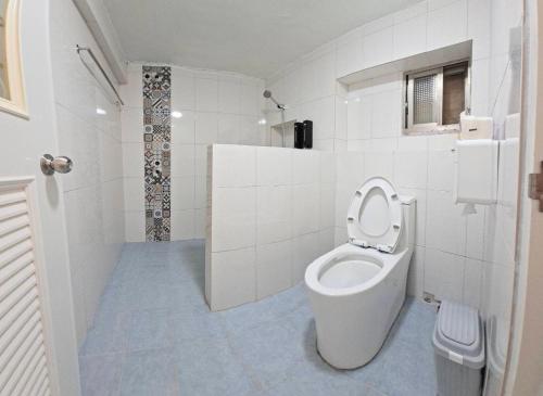 a white bathroom with a toilet and a shower at 龍磐1號民宿 全家出遊首選1至12人包棟 均一價 免爬梯獨棟平房 三間獨立套房 寬敞庭院可烤肉 in Eluan