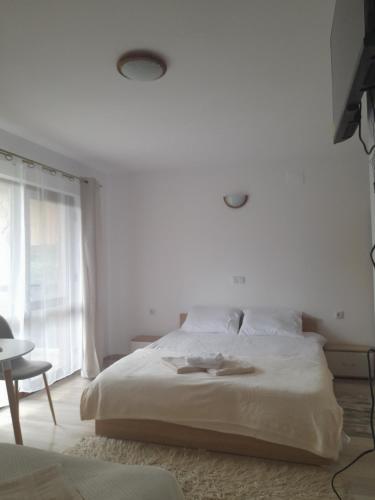 a white bedroom with a bed and a window at Cabana Andrea in Arpaşu de Sus