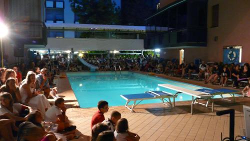 uma multidão de pessoas sentadas à volta de uma piscina em Hotel Christian em Rimini