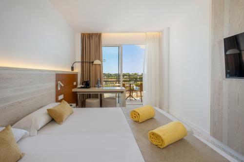 a bedroom with a large white bed with yellow pillows at Cabot Cala Ferrera in Cala d´Or