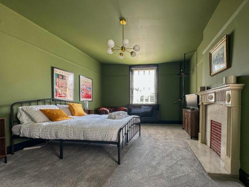 a green bedroom with a bed and a fireplace at Cheshire Yeoman - Station Hotel in Hooton Station