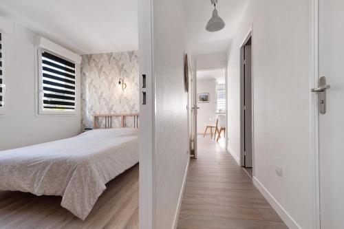 a white bedroom with a bed and a hallway at Les Marines Du Crouesty in Arzon