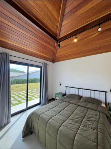 a bedroom with a large bed and a large window at Nosso Loft Sebollas - 4C in Paraíba do Sul