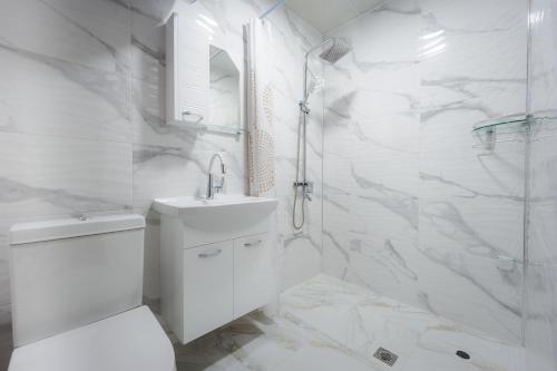a white bathroom with a sink and a shower at Къща за гости Вихрен-Сандански in Sandanski