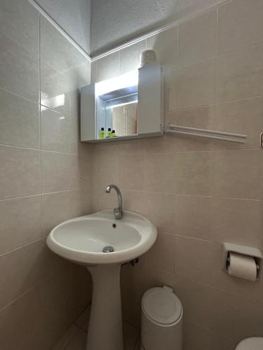 a bathroom with a sink and a toilet and a mirror at Art Hotel Panorama in Pyrgadikia