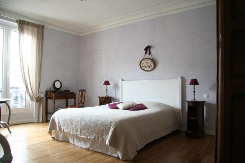 a bedroom with a bed and a clock on the wall at Chambres d'hôtes Le Clos d'Hauteville in Le Mans
