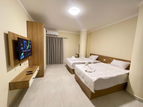 a hotel room with two beds and a flat screen tv at Downtown Keys in Hurghada
