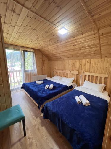 a bedroom with two beds in a wooden cabin at Alpine Lodge Bakhmaro in Chʼkhakoura
