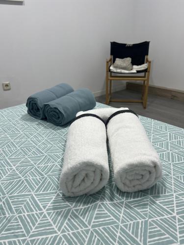 a bed with towels on it with a chair at A&R Santiago de Compostela in San Sebastián de los Reyes
