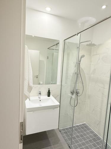 a white bathroom with a shower and a sink at The Lennox D-Plus Apartments in Accra