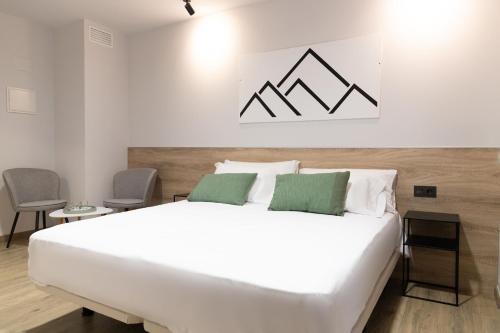 a bedroom with a large white bed with two green pillows at Inkigo Rooms in Jaca