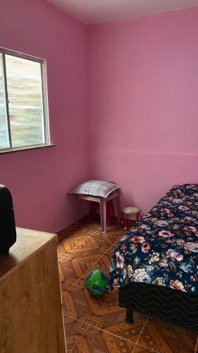 a bedroom with pink walls and a bed and a bench at Casa completa com piscina 12min da praia in Porto Seguro