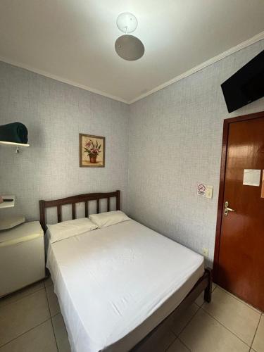 a bedroom with a white bed in a room at Hotel Savana in Olímpia