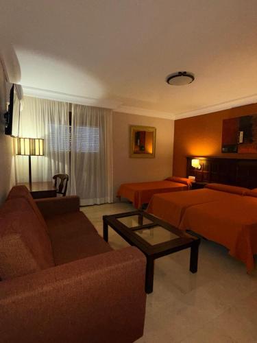 a hotel room with two beds and a couch at Hotel Sierra Hidalga in Ronda