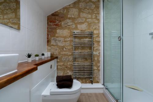 a bathroom with a toilet and a glass shower at Tove Valley Cottages in Towcester