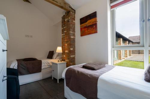 a bedroom with two beds and a window at Tove Valley Cottages in Towcester