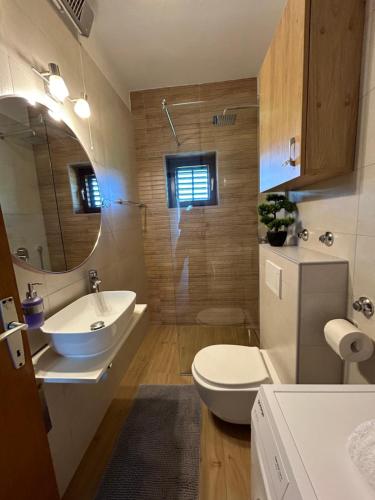 a bathroom with a sink and a toilet and a mirror at Apartment Roko (10m from the beach) in Pašman