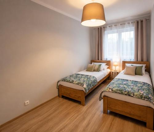 two beds in a room with a window at Apartament 1go Maja TK in Namysłów