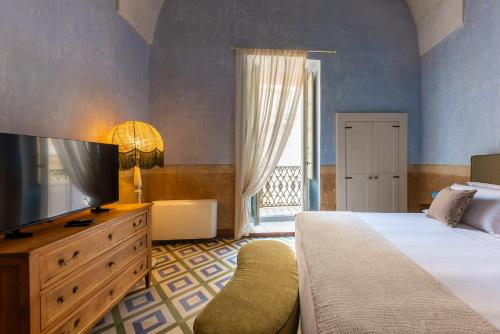 a bedroom with a bed and a dresser with a television at Palazzo Venneri Lloyd - Historic Heritage Palazzo in Gallipoli